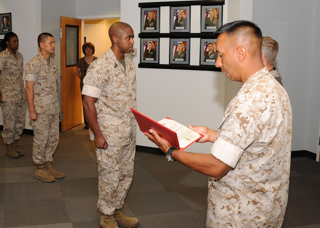 Headquarters Battalion enlisted leader 1st Sgt. Arthur Hernandez (right) reads the citation of the Navy and Marine Corps Commendation Medal awarded to Marine Corps Logistics Base Barstow Supply Chief Master Sgt. Lorenzo Lacy (center) June 9, following his six-month overseas deployment in support of Marine Central Command.